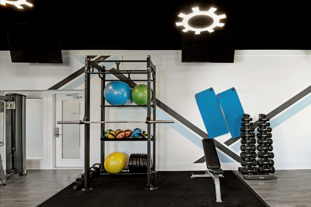 A new squat rack and storage space cutout within an apartment complex's fitness space.